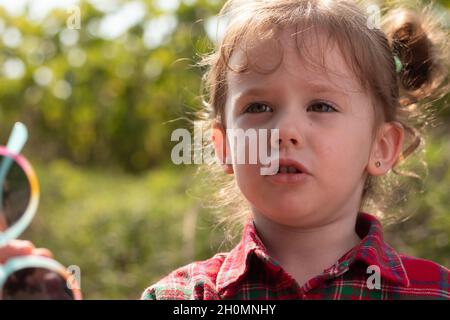 Bella ragazza bionda ricurly in una camicia rossa a quadri su sfondo naturale sfocato Foto Stock