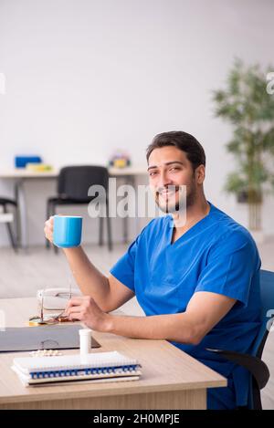 Giovane medico che beve caffè durante la pausa Foto Stock