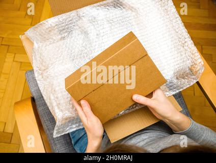 Vista dall'alto di una donna curiosa che sboxe nel soggiorno nuovo pacchetto argento consegna Foto Stock