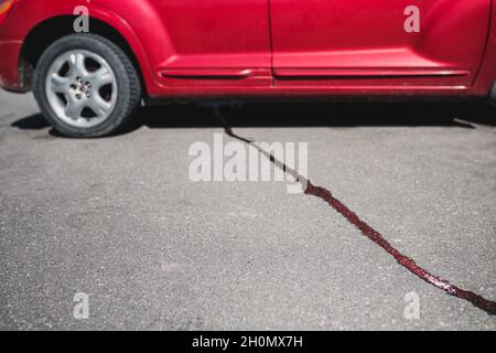 Un flusso di liquido sul marciapiede da sotto la vettura - l'olio fluisce dal motore Foto Stock