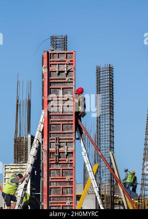 Operai edili che assemblano casseforme per colonne in calcestruzzo in cantiere Foto Stock