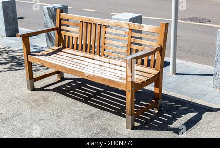 Panca in legno presso la strada di città in estate giornata di sole Foto Stock