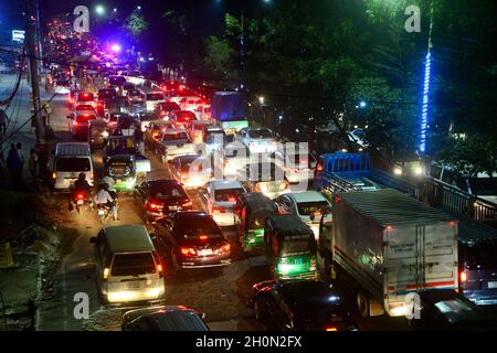 I pendolari si fanno strada attraverso un ingorgo di traffico di notte durante la Pandemia di Coronavirus di Covid-19 a Dhaka, Bangladesh, il 13 ottobre 2021.ultimi 10 anni a Dhaka, la velocità media del traffico è scesa da 21 km/ora a 7 km/ora, solo leggermente al di sopra della velocità media di camminata. La congestione in Dhaka mangia fino a 3.2 milioni di ore lavorative al giorno secondo i rapporti statici. Foto Stock