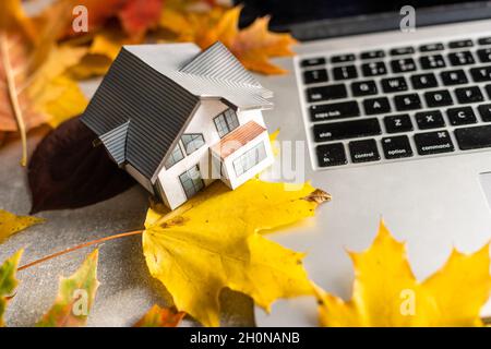 mockup modello casa e lascia vicino computer portatile su un tavolo. Stagione autunnale Foto Stock
