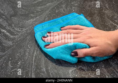 Pulizia del piano di lavoro. Cura dei countertops nella cucina o nella stanza da bagno. Pulizia di superfici in pietra, marmo o pietra artificiale. Salviette per le mani da donna Foto Stock