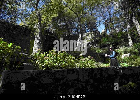 Sintra, Portogallo. 8 Ott 2021. Una donna cammina vicino al secondo muro di protezione nei dintorni del forte di Castelo dos Mouros. Il Castelo dos Mouros (Castello moresco), dichiarato patrimonio dell'umanità dall'UNESCO, deve il suo nome al passato dell'occupazione musulmana del Portogallo, serve per la sua posizione ottimale in cima come punto di posizione strategica con una vista completa dei dintorni. Il Castello moresco fu conquistato nel 1154 dai cristiani. Nel 19 ° secolo, re Fernando II del Portogallo ha ordinato la sua ricostruzione per integrarla con i giardini del Palazzo pena, recuperare Foto Stock