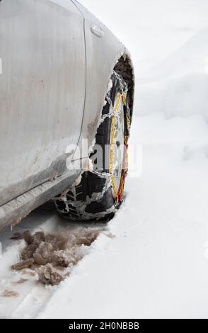 Vista posteriore delle catene degli pneumatici sulle ruote di un veicolo sporco nella neve Foto Stock