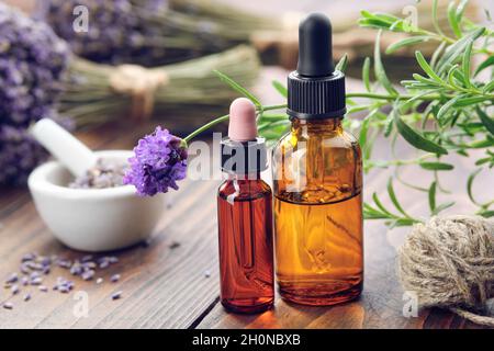 Bottiglie contagocce di olio essenziale di lavanda, fiori freschi ed essiccati di lavanda sullo sfondo. Foto Stock