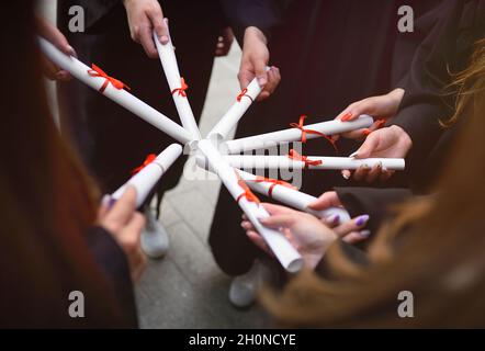 laureati in abiti neri con diplomi o certificati di laurea presso un istituto di istruzione superiore. Foto Stock