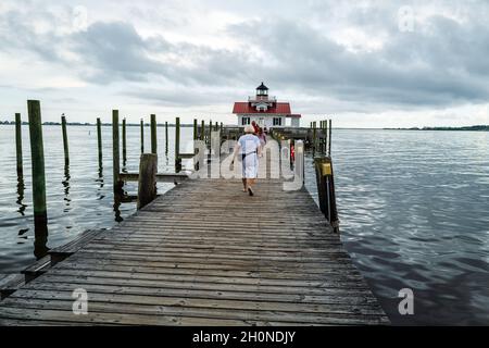 Manteo, NC, USA — 15 agosto 2021. Foto grandangolare persone che camminano sul lungomare che conduce al faro delle paludi di Roanoke. Foto Stock