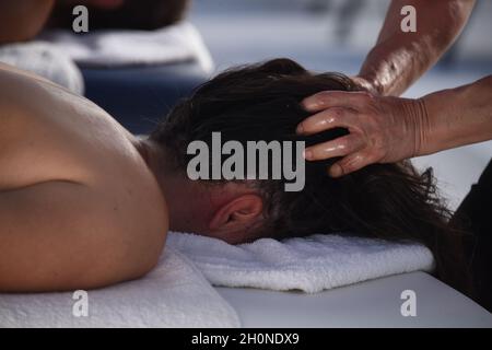 Il giovane si gode di un massaggio nel salone termale Foto Stock