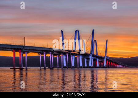 Il Governatore Mario M. Cuomo Bridge, illuminato in rosso, bianco e blu in riconoscimento del Columbus Day, attraversa il fiume Hudson subito dopo il tramonto. Foto Stock