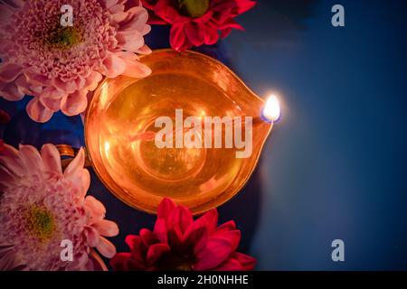 Festeggia il festival indiano di luce Diwali. Primo piano di tradizionali lampade ad olio di diya e fiori su sfondo blu. Foto Stock