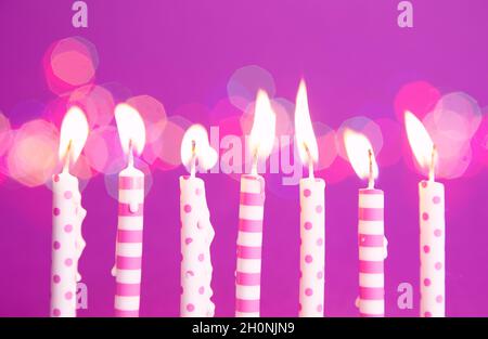 Candele di compleanno bruciate su sfondo viola Foto Stock
