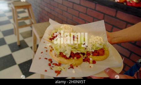 Tacos nelle mani di un cameriere Foto Stock