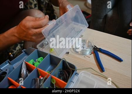 sul tavolo sono appoggiate scatole di plastica con attrezzi da pesca aperti Foto Stock