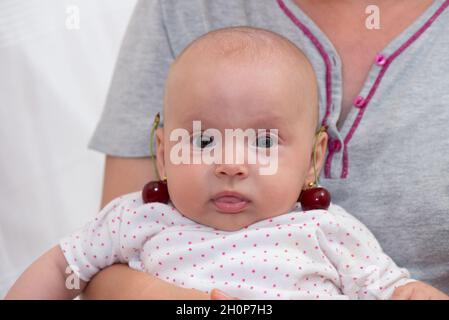 Bambina con ciliegie sulle orecchie Foto Stock