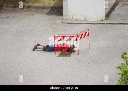 Il lavoratore posa i cavi in fibra ottica per il cablaggio della città utilizzando le infrastrutture esistenti Foto Stock