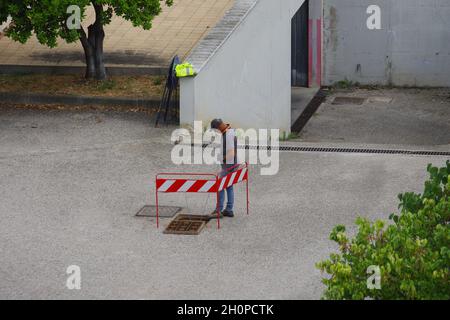 Il lavoratore posa i cavi in fibra ottica per il cablaggio della città utilizzando le infrastrutture esistenti Foto Stock