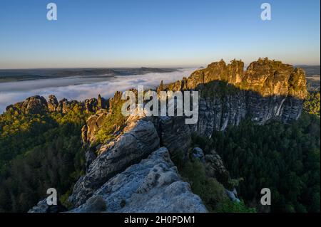 Bad Schandau, Germania. 10 Ott 2021. Vista dal punto di osservazione di Schrammstein nella Svizzera sassone delle rocce della Schrammsteine e della nebbia che passa nella valle dell'Elba. La bassa catena montuosa, costituita principalmente da arenaria, si estende per circa 700 kmq sulle vette superiori dell'Elba. La parte tedesca si chiama Svizzera sassone, la parte ceca Svizzera boema. Credit: Robert Michael/dpa-Zentralbild/dpa/Alamy Live News Foto Stock