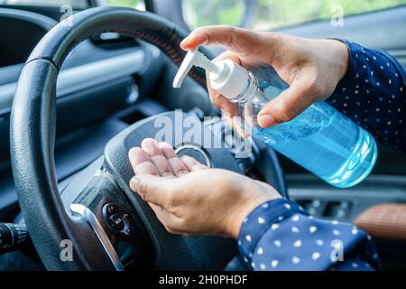 New Normal, Asian lavoro donna lavaggio mano da press blu alcol sanitizzante gel per proteggere la sicurezza Coronavirus in auto. Foto Stock