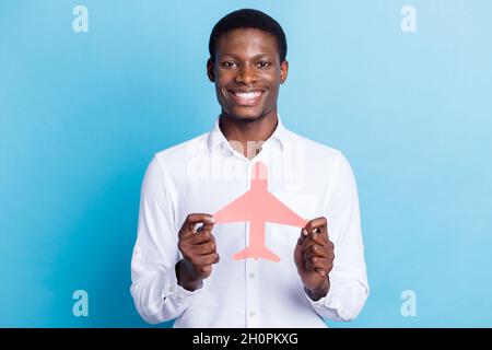 Foto di affascinante piuttosto scuro ragazzo pelle vestito formale camicia tenendo piano di carta rosa sorridente isolato blu sfondo di colore Foto Stock