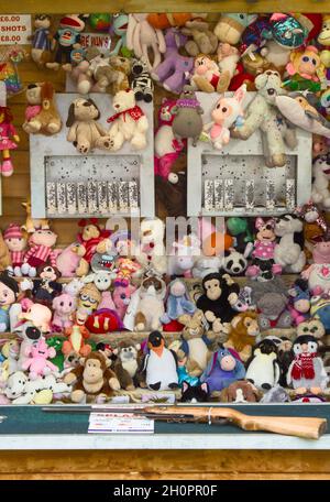 Shooting Gallery Stall con pistola e obiettivi fissati tra un sacco di Fluffy Toy Prizes, Funfair UK Foto Stock