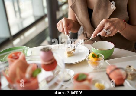 primo piano di mani di una donna asiatica cliente che mangia dessert in un raffinato ristorante Foto Stock