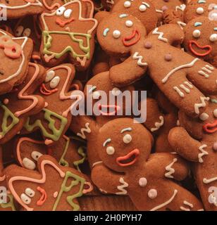 Sfondo di biscotti di zenzero natalizi fatti in casa appena sfornati a forma di uomini sorridenti e stelle di mare Patrick decorato con smalto colorato sul tavolo Foto Stock