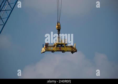 Spanditore automatico di una gru industriale sospesa in aria con fondo cielo blu Foto Stock