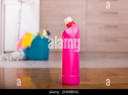 Bottiglia di prodotto per la pulizia sul pavimento della cucina con secchio e attrezzatura di pulizia di fronte agli armadi in background Foto Stock