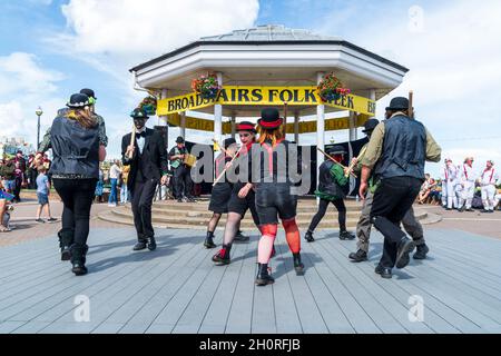 Scopa mattoni e Bowlers Manic Morris uomini ballare di fronte al Bandstand sul lungomare durante l'annuale Broadstairs Folk Week festival. Foto Stock