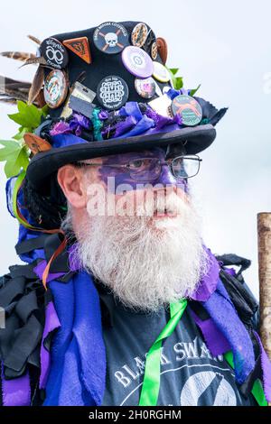 Volto di uomo maturo con barba bianca, con occhiali e cappello nero festooned con badge, un membro dei ballerini Morris Border Black Swan. Foto Stock