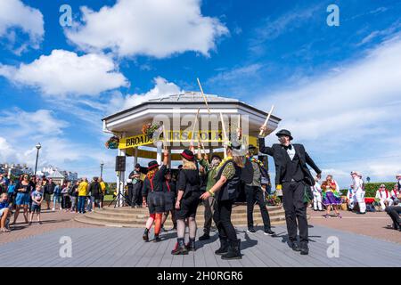 Scopa mattoni e Bowlers Manic Morris uomini ballare di fronte al Bandstand sul lungomare durante l'annuale Broadstairs Folk Week festival. Foto Stock