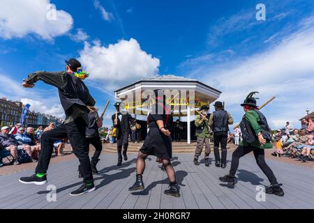 Scopa mattoni e Bowlers Manic Morris uomini ballare di fronte al Bandstand sul lungomare durante l'annuale Broadstairs Folk Week festival. Foto Stock