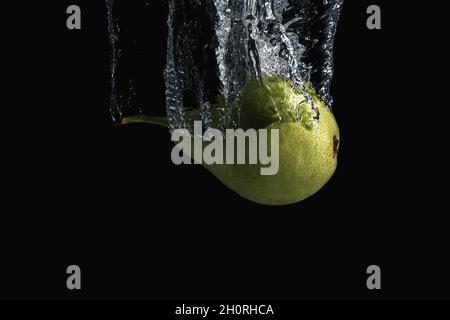 Pera verde fresca in acqua splash isolato su sfondo nero. Concetto minimo di cibo. Foto Stock