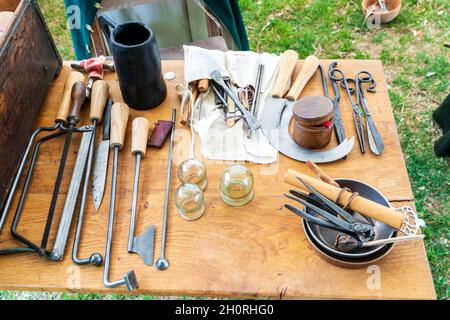 Mostra medievale di storia vivente. Strumenti per i chirurghi Barber, tra cui coltelli per amputazione, seghe e bottiglie di leeching visualizzate su un tavolo di legno. Foto Stock