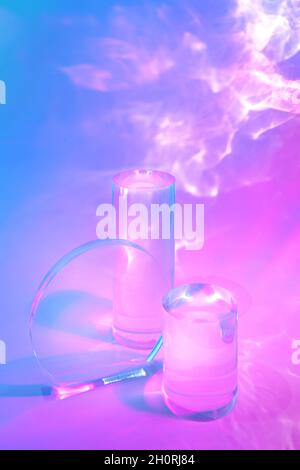 due podi in vetro trasparente su sfondo pastello al neon Foto Stock