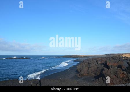 Belle onde che ondolano a riva su una spiaggia di sabbia di roccia lavica nera. Foto Stock