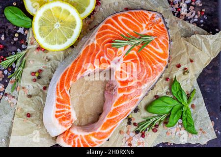 Salmoni rossi crudi fette di pesce con spezie, rosmarino e limone in cucina su sfondo chiaro. Foto Stock