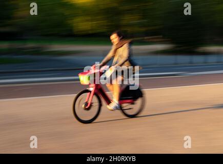 Ciclista su South Carriage Drive, Hyde Park, Londra; movimento veloce che produce immagini sfocate Foto Stock