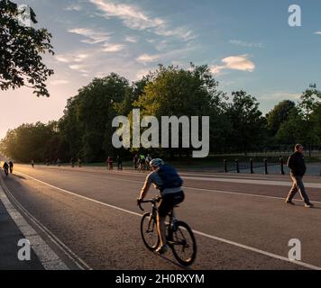 Ciclista su South Carriage Drive, Hyde Park, Londra; movimento veloce che produce immagini sfocate Foto Stock