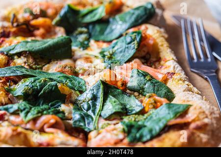 Pizza fatta in casa con salmone, spinaci, pesto e gamberetti, primo piano. Concetto di cibo confortevole. Foto Stock