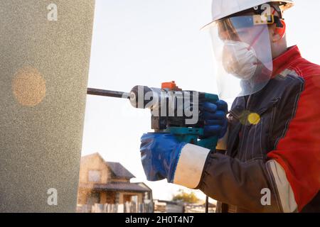Un attrezzo di montaggio maschio funziona con un martello perforatore. Lavori di costruzione Foto Stock