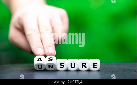 La mano gira i dadi e cambia la parola incerto per assicurare. Foto Stock