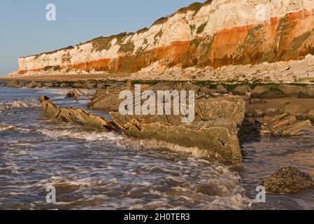 I resti del relitto dello Sheraton sulla spiaggia a North Beach, Hunstanton, Norfolk, Inghilterra, Regno Unito, Mostra anche le scogliere a strisce rosa e bianche Foto Stock