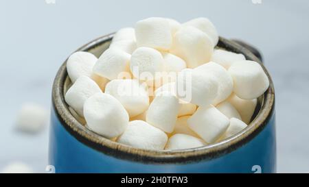 Marshmallow in tazza da caffè da primo piano con fondo morbido blu chiaro Foto Stock