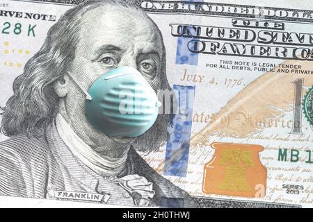 Primo piano della valuta della carta degli Stati Uniti cento dollari fattura con Benjamin Franklin che indossa la maschera blu del viso a causa di COVID-19 pandemic che rende un grande Foto Stock