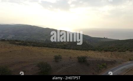 Vista aerea. Volo su una verde erbosa colline rocciose. Volare sulle alte montagne in bellissime nuvole. Foto Stock