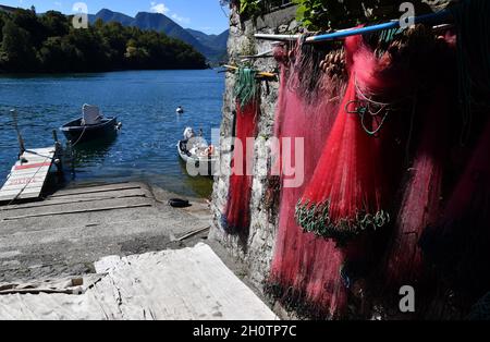 Reti di pescatori che si asciugano al sole con airone sulla barca da pesca Sala Comacina, Lago di Como, Italia Foto Stock